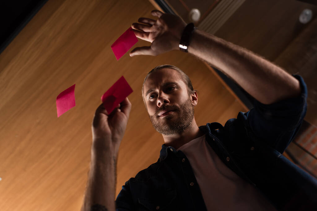 low angle view of bearded businessman looking at sticky note - Photo, Image