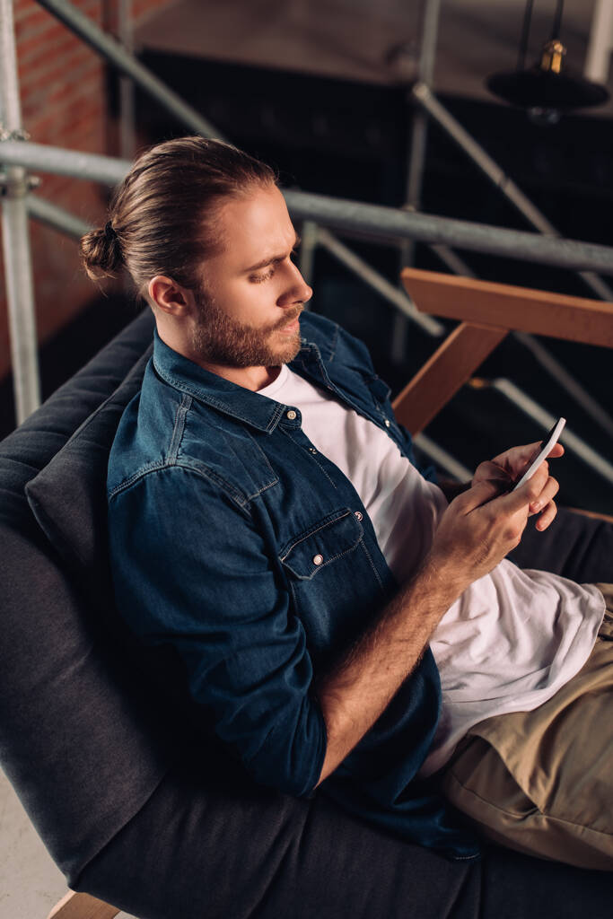 handsome businessman chilling on sofa and using smartphone in office  - Photo, Image