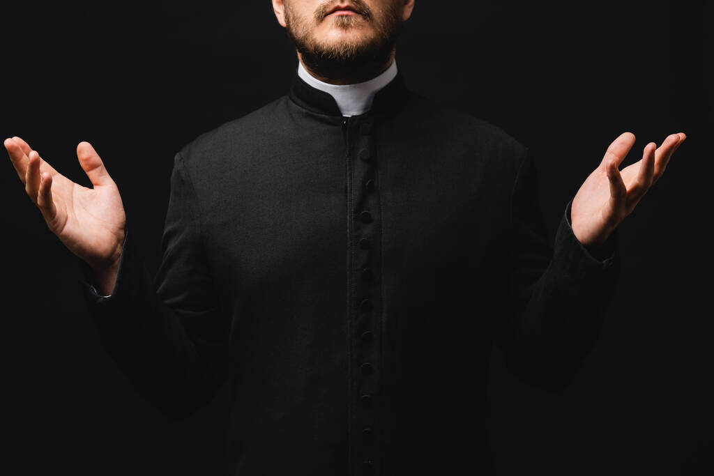 καλλιεργημένη άποψη του ιερέα με απλωμένα χέρια απομονώνονται σε μαύρο  - Φωτογραφία, εικόνα
