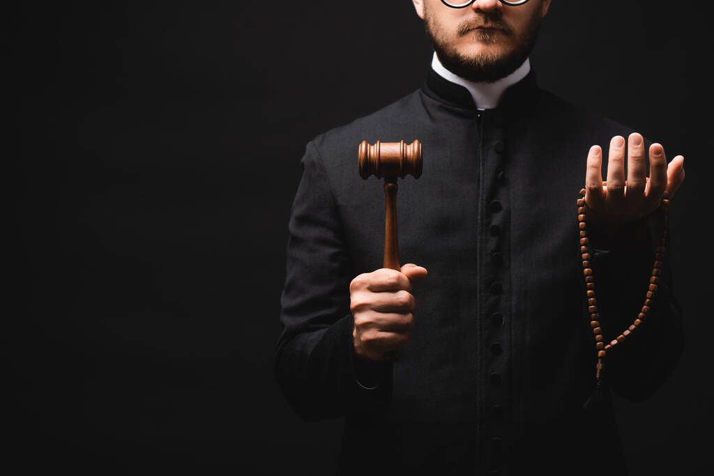 vista ritagliata del sacerdote barbuto che tiene martelletto di legno e rosario perline isolate su nero  - Foto, immagini