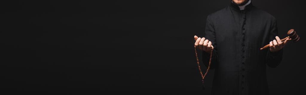 plan panoramique d'un prêtre tenant un marteau en bois et des perles de chapelet dans des mains isolées sur du noir  - Photo, image