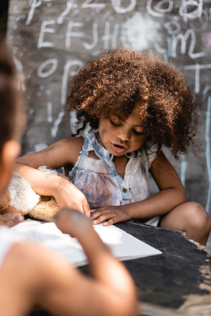 selektivní zaměření chudých afrických amerických dětí psaní v blízkosti bratra během lekce  - Fotografie, Obrázek