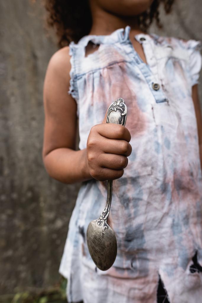 都市の通りに汚れたスプーンを保持貧しいアフリカ系アメリカ人の子供の作物ビュー  - 写真・画像