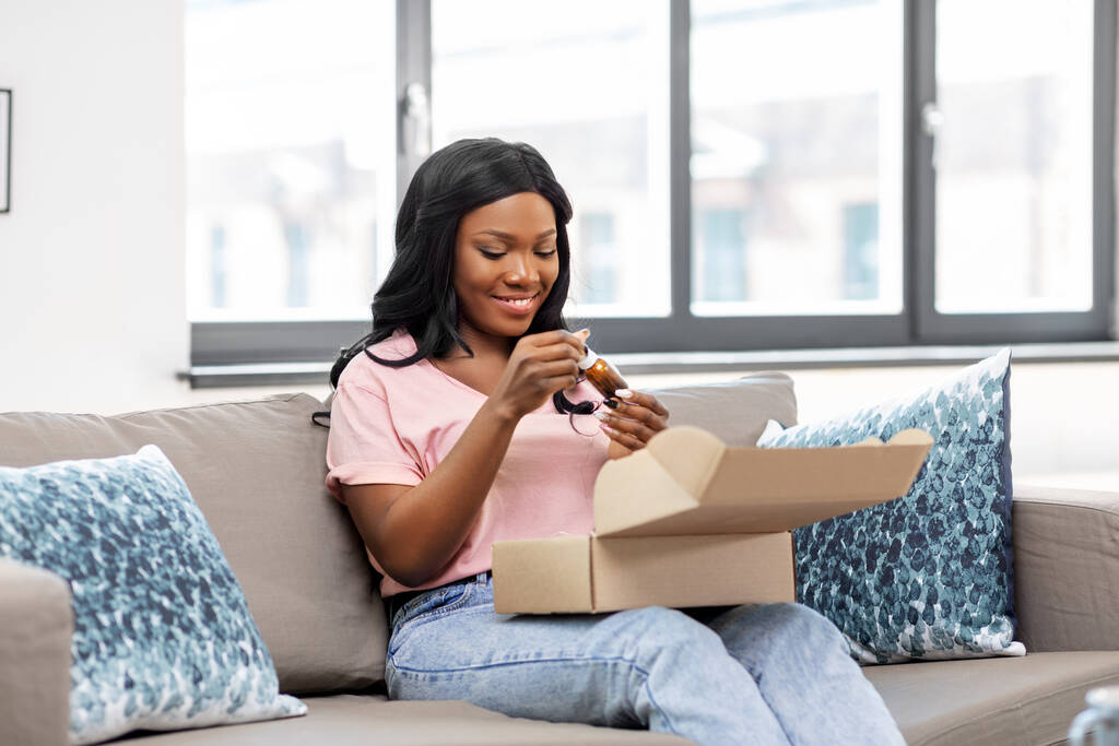 Африканская американка открывает коробку с посылками дома - Фото, изображение