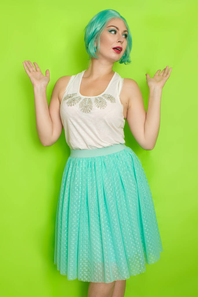Retrato de una hermosa joven con el pelo azul corto en un estudio sobre un fondo verde. Falda romántica de mediana longitud y blusa blanca
 - Foto, imagen