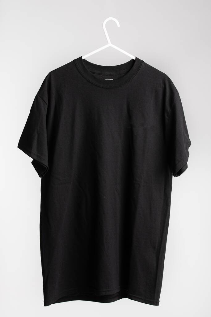 Uma camisa de manga curta no cabide de pano com parede branca no fundo
 - Foto, Imagem