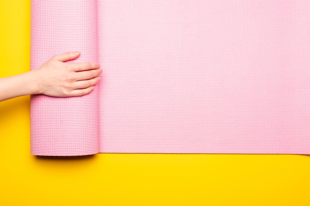 обрезанный вид женщины прокатки розовый коврик фитнес на желтом фоне - Фото, изображение