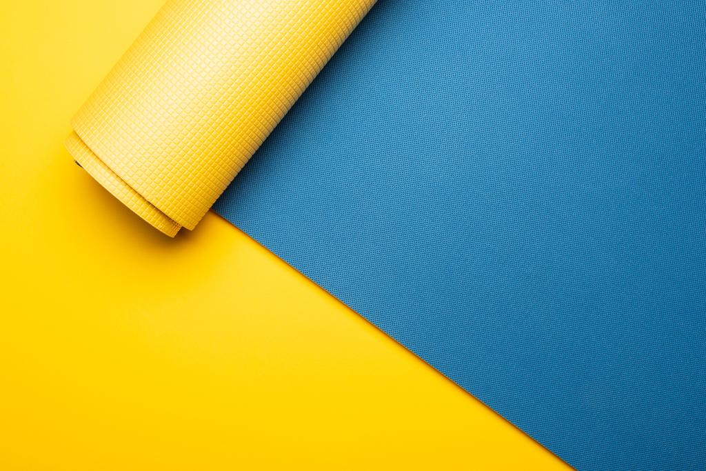 vista dall'alto del tappeto fitness blu su sfondo giallo - Foto, immagini