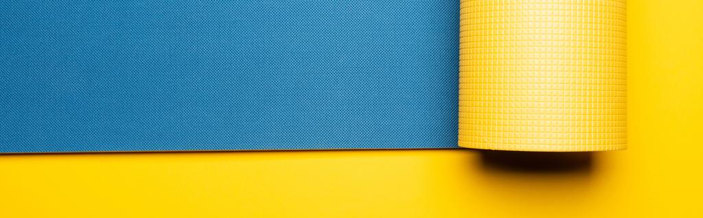 vue de dessus du tapis de fitness bleu sur fond jaune, panoramique - Photo, image