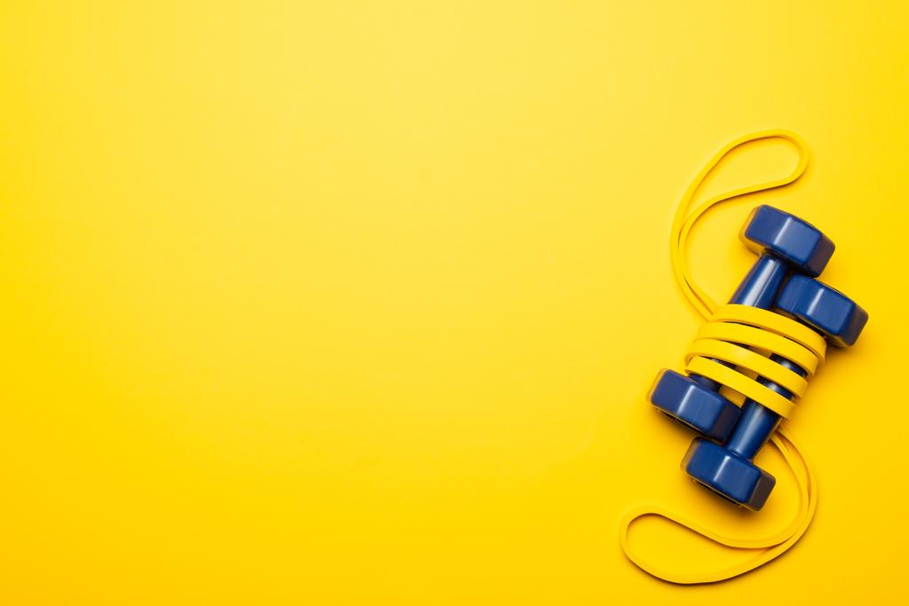 верхний вид синих гантелей в полосе сопротивления на желтом фоне - Фото, изображение