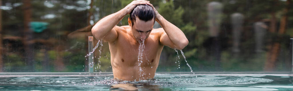 panoramic concept of wet and muscular man touching hair in swimming pool - Photo, Image