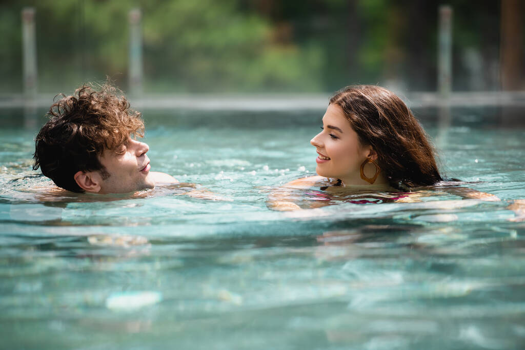 селективное внимание счастливого мужчины и женщины, плавающих в бассейне
  - Фото, изображение