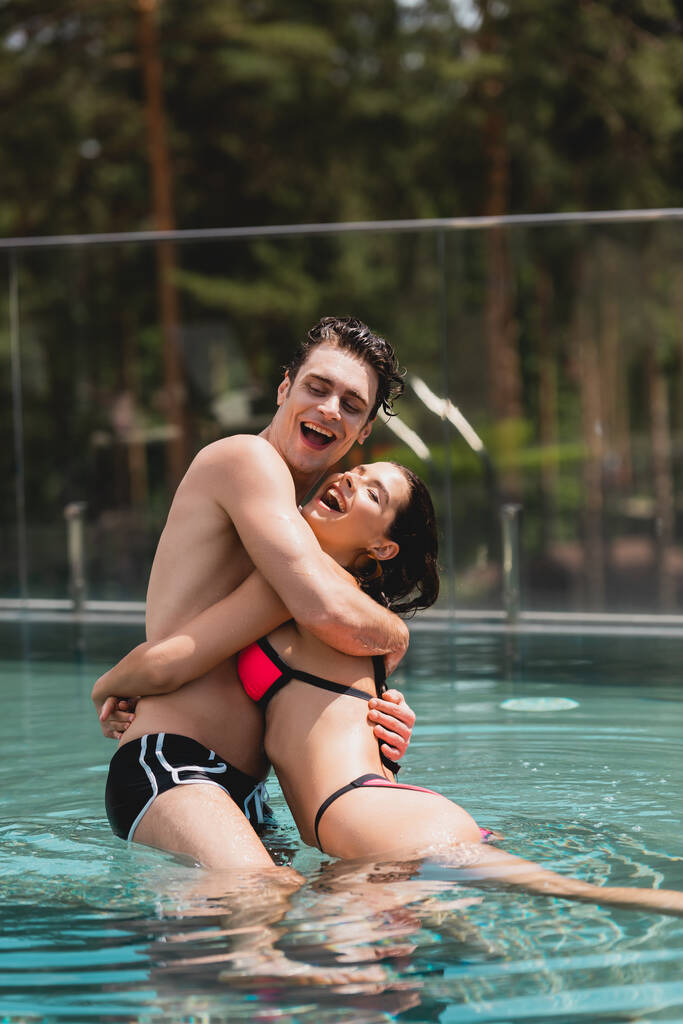 feliz pareja en traje de baño abrazos en la piscina
  - Foto, Imagen
