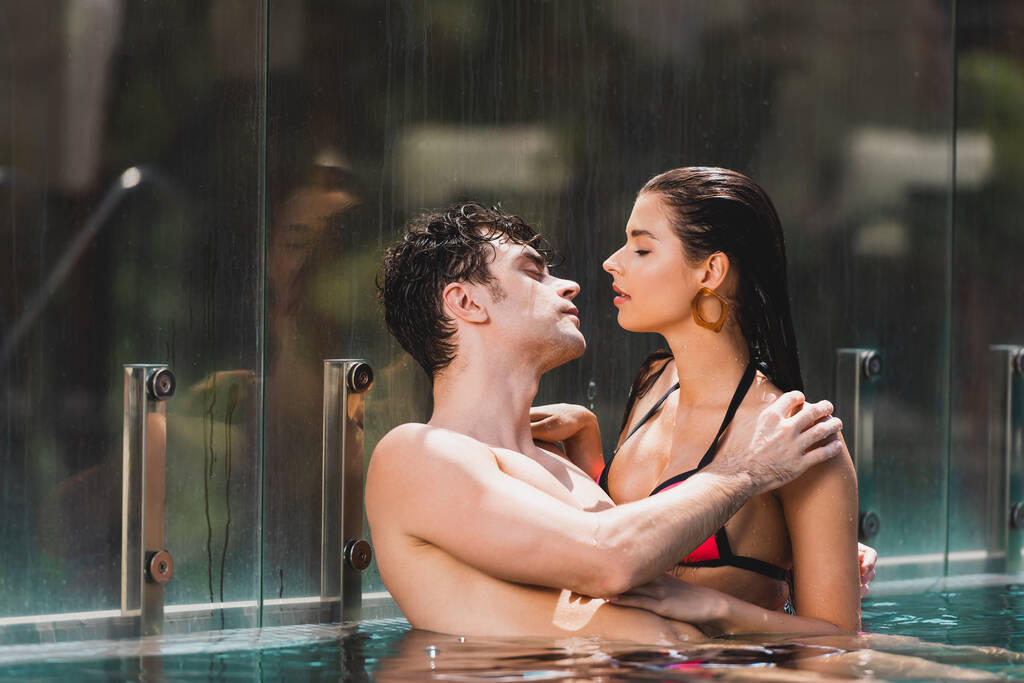 side view of sexy couple looking at each other in swimming pool  - Photo, Image