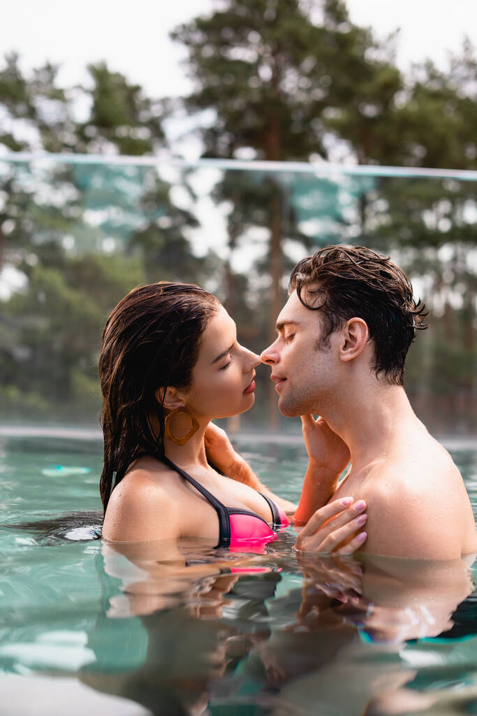 vista lateral de pareja con los ojos cerrados en la piscina
 - Foto, imagen