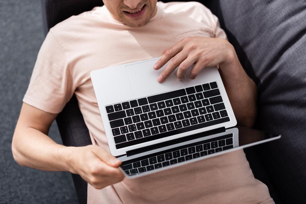 Вид сверху на фрилансера, использующего ноутбук с экраном, лежа на диване дома, концепция заработка онлайн - Фото, изображение
