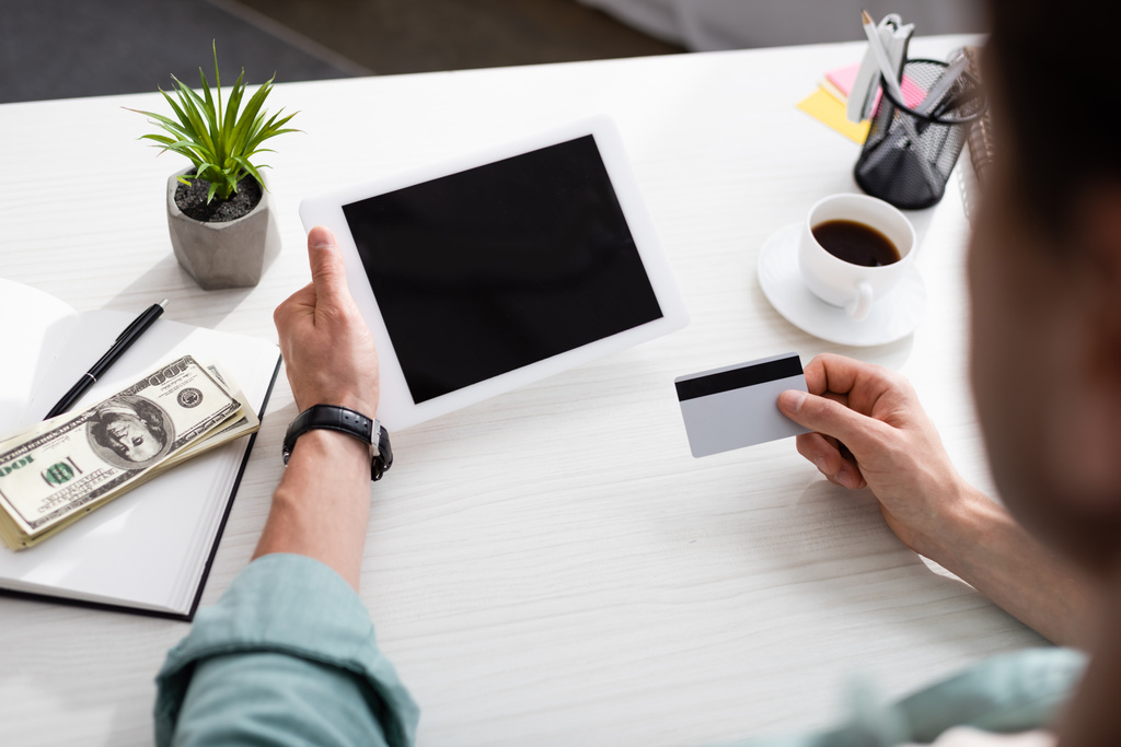 Valikoiva painopiste mies, jolla luottokortti ja digitaalinen tabletti lähellä käteistä kannettavan ja kahvin pöydällä, ansaita online-konsepti - Valokuva, kuva