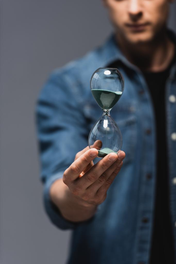 Cropped view of young man holding hourglass isolated on grey, concept of time management  - Photo, Image
