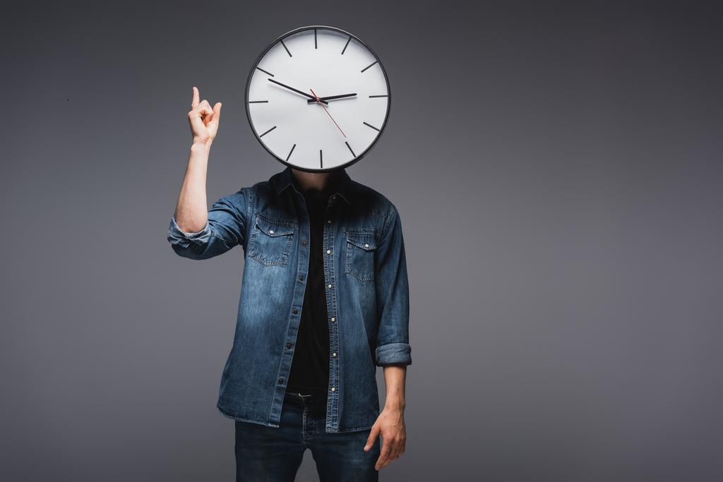 Mann mit Zifferblatt in Uhrennähe zeigt mit Fingern auf grauem Hintergrund, Konzept des Zeitmanagements  - Foto, Bild