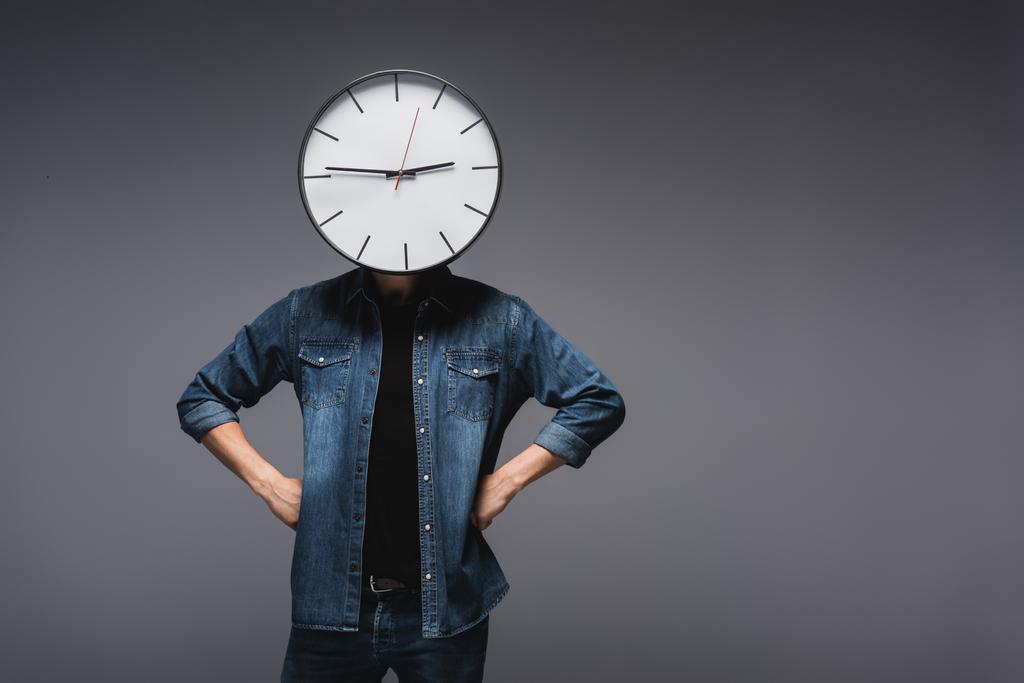 Homme avec horloge sur la tête et les mains sur les hanches sur fond gris, concept de gestion du temps  - Photo, image