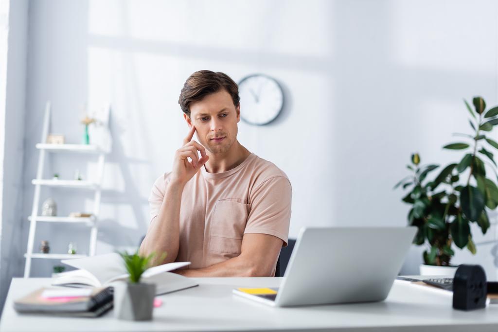 Επιλεκτική εστίαση στοχαστικός άνθρωπος κοιτάζοντας φορητό υπολογιστή, ενώ εργάζονται στο σπίτι, κερδίζοντας online έννοια - Φωτογραφία, εικόνα