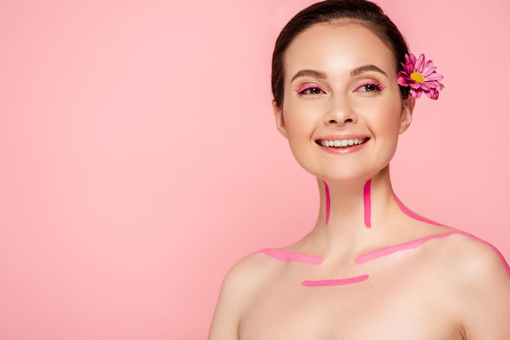 smiling naked beautiful woman with pink lines on body and flower in hair isolated on pink - Photo, Image