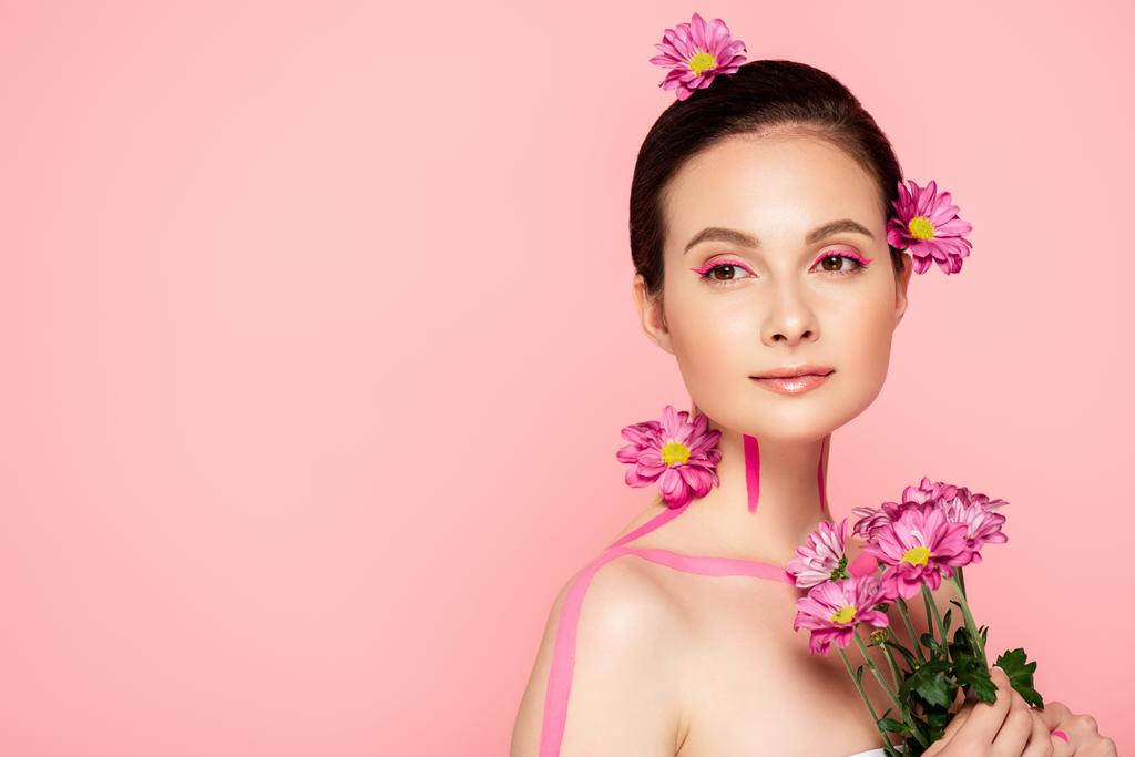 naakt mooi vrouw met roze lijnen op lichaam en bloemen in haar bedrijf boeket geïsoleerd op roze - Foto, afbeelding
