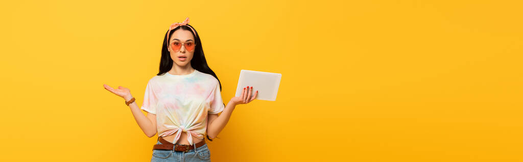 плутанина стильна літня брюнетка дівчина тримає цифровий планшет на жовтому фоні, панорамний знімок
 - Фото, зображення
