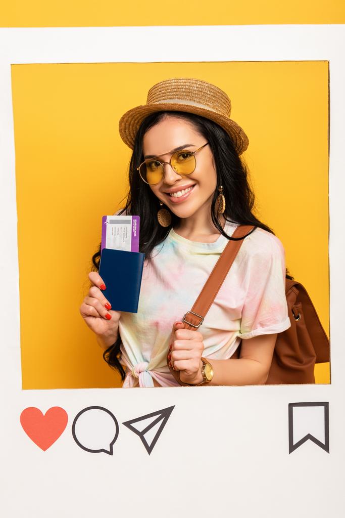 щаслива дівчина брюнетка в літньому вбранні тримає авіаквиток у соціальній мережі на жовтому фоні
 - Фото, зображення