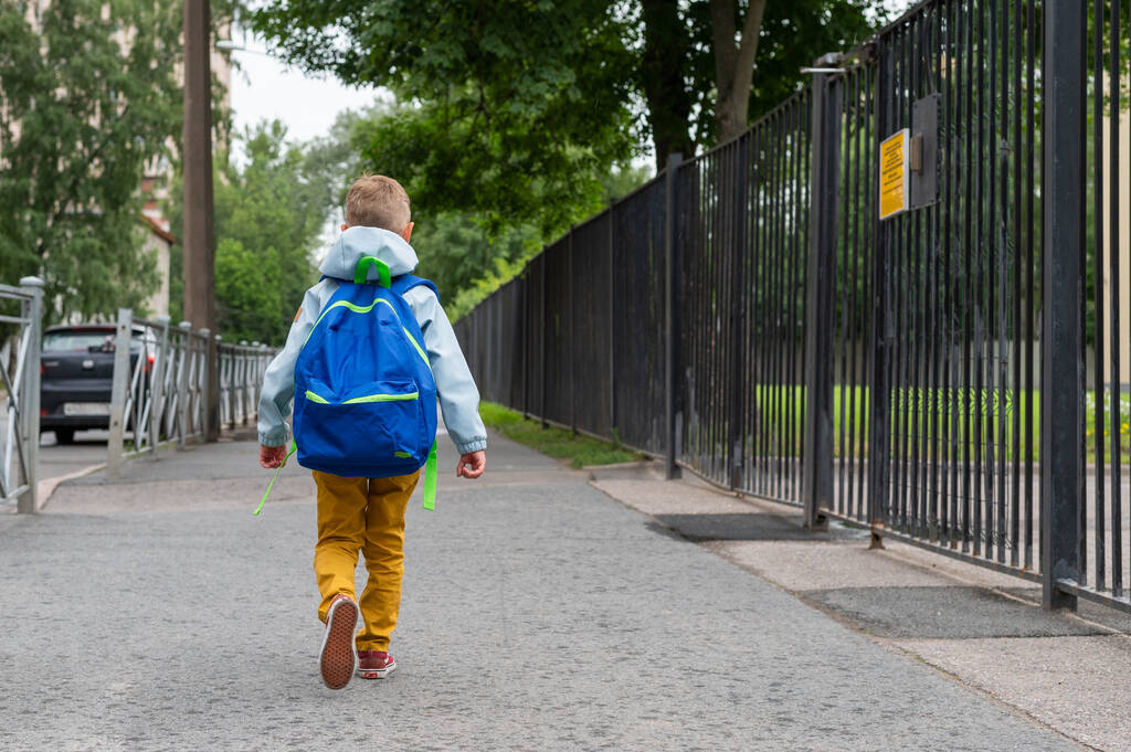 Mavi çantalı küçük bir çocuk okula gidiyor. Bir çocuk ilk kez ilkokula gider. Okula geri dön.. - Fotoğraf, Görsel