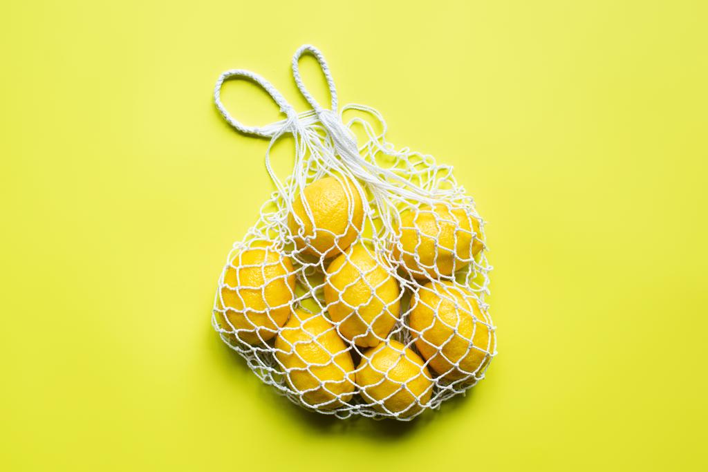 widok z góry dojrzałych całych cytryn w worek sznurkowy na żółtym tle - Zdjęcie, obraz