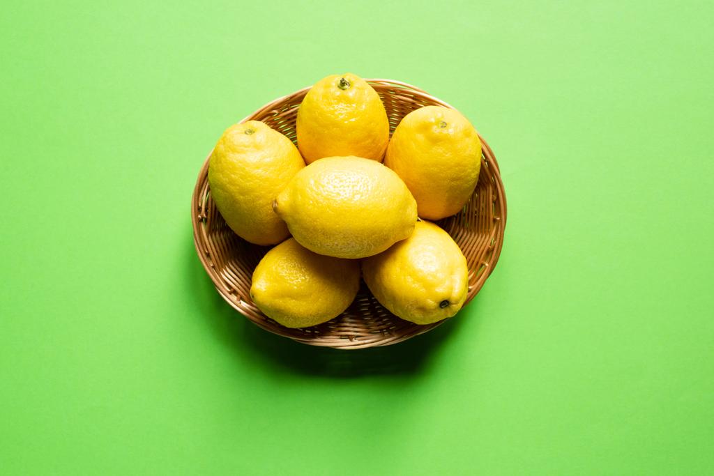 limones amarillos maduros en canasta de mimbre sobre fondo verde
 - Foto, imagen