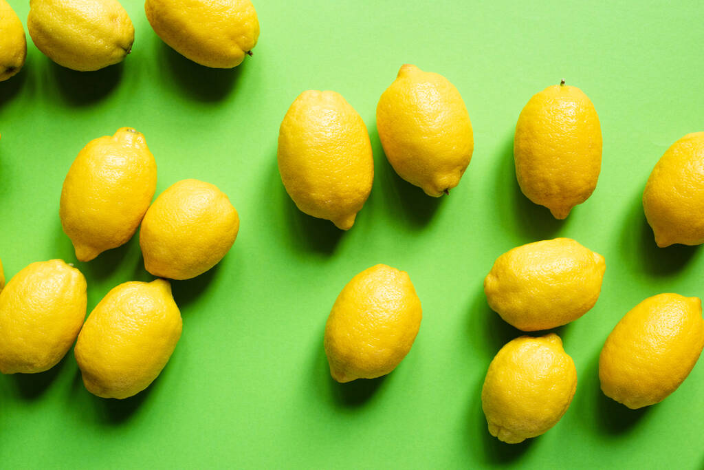 vista superior de limones amarillos maduros esparcidos sobre fondo verde
 - Foto, imagen
