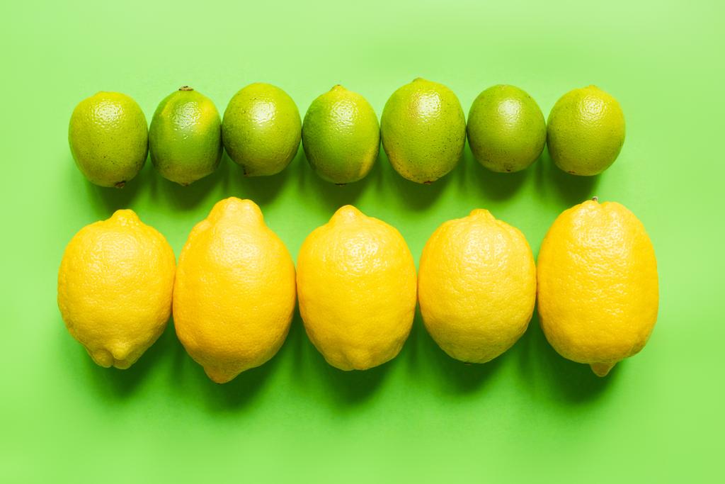 плоский лежал со спелыми лимонами и лаймами на зеленом фоне - Фото, изображение