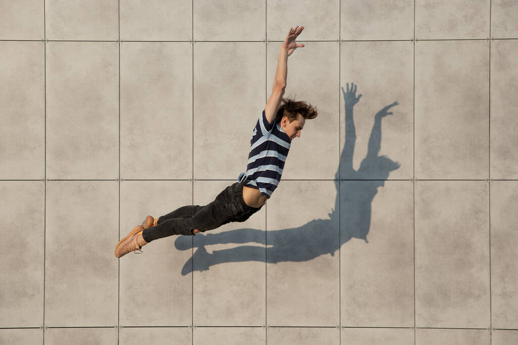Прыжки молодой бизнесмен перед зданиями, на бегу в прыжке высоко - Фото, изображение