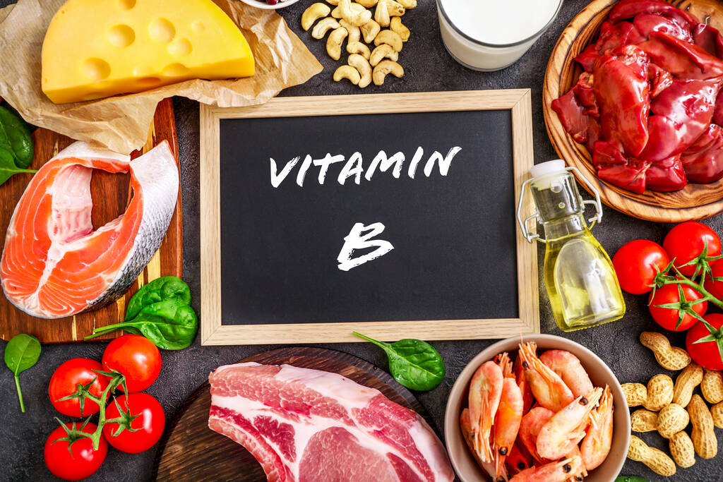 Vitamin B Complex for Men's Health. Assortment of high vitamin B sources on dark background: milk, liver, olive oil, tomatoes, prawns, peanuts, beef, spinach, salmon, keshew, cheese. Top view. - Photo, Image