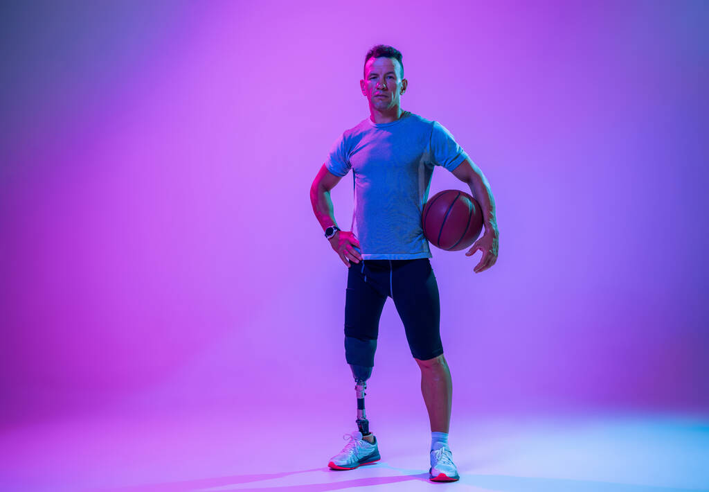 グラデーションスタジオの背景に孤立した障害者や切断者を持つアスリート。プロの男性バスケットボール選手で脚の義肢トレーニングとスタジオでの練習. - 写真・画像