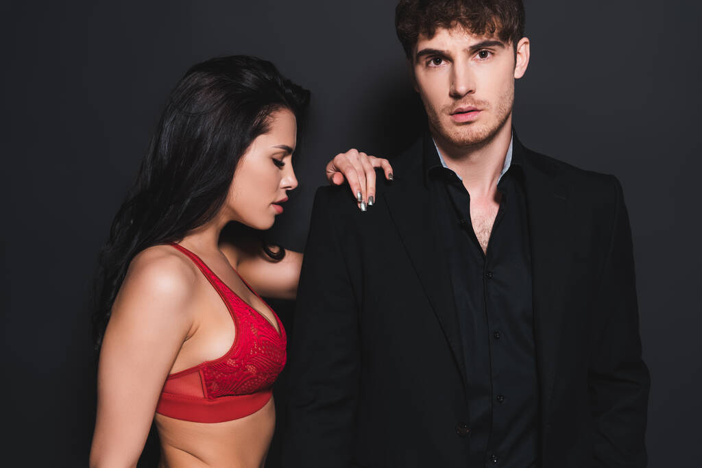 sexy mujer en rojo y encaje sujetador tocando guapo hombre en negro
  - Foto, Imagen