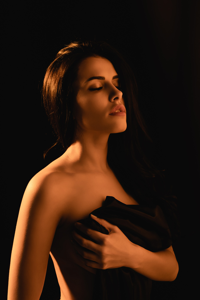 iluminación en la mujer sensual con los ojos cerrados envueltos en sábana de seda aislado en negro
  - Foto, imagen