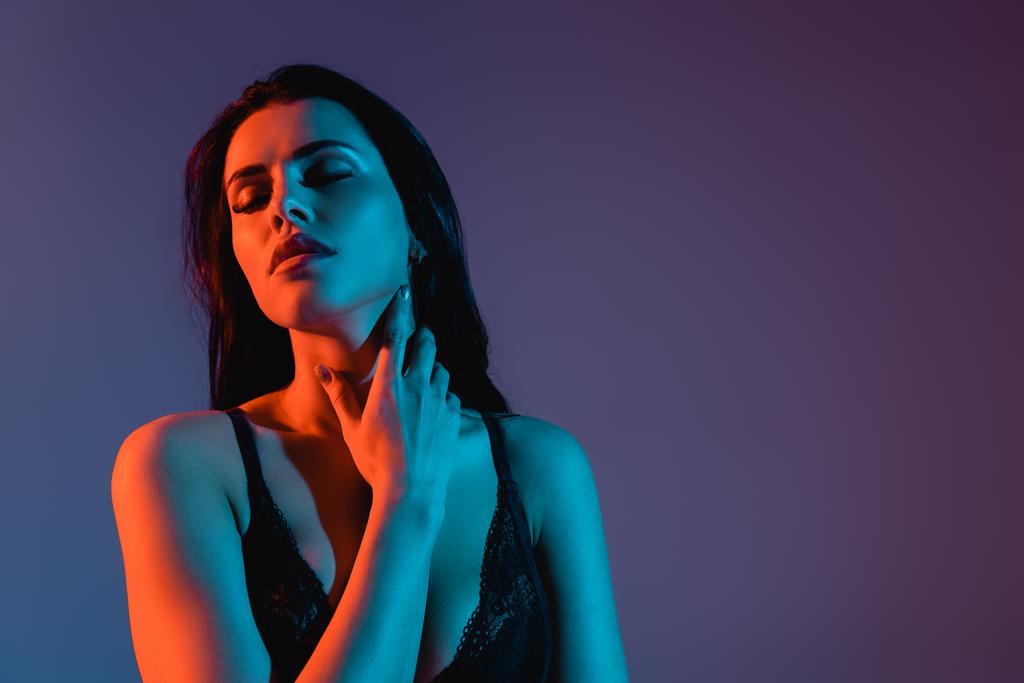 sexy jonge vrouw met gesloten ogen aanraken hals geïsoleerd op paars  - Foto, afbeelding