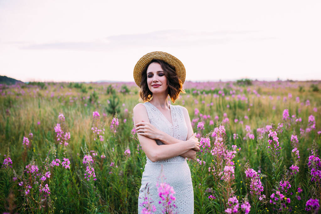 uma menina em um chapéu de palha em um campo de flores
 - Foto, Imagem