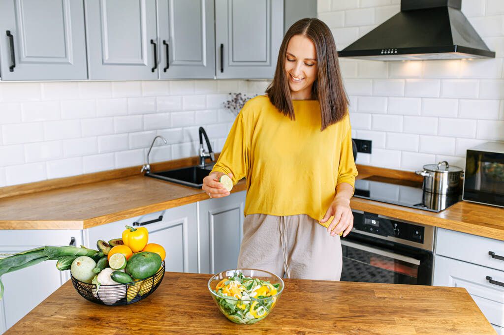 Eine fröhliche Frau bereitet einen Salat zu - Foto, Bild