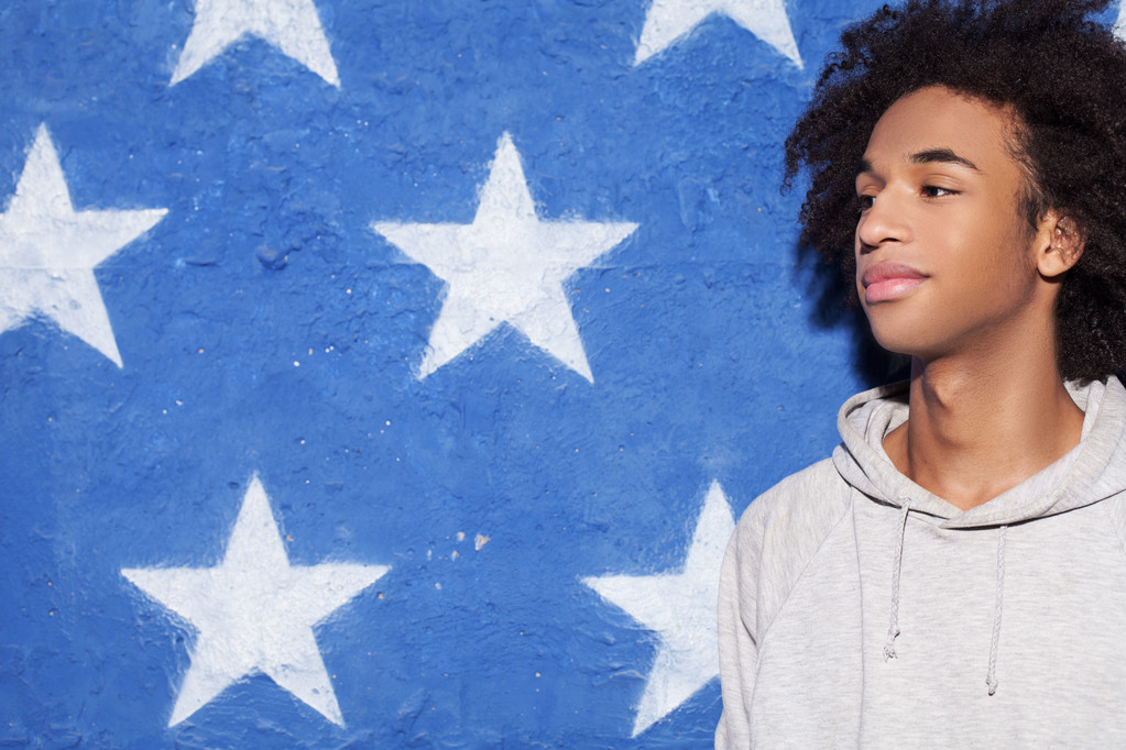 ¡Tranquilo! Joven hombre africano de pie contra la bandera americana y mirando hacia otro lado
 - Foto, imagen