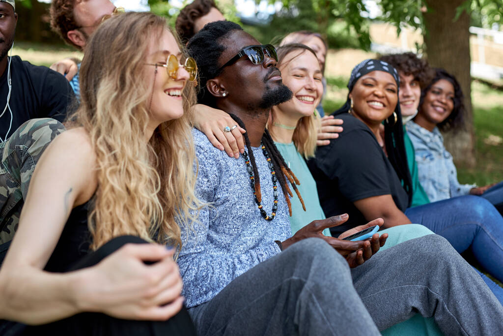amerikaanse gemengde ras jeugd zitten op gras samen en plezier hebben - Foto, afbeelding