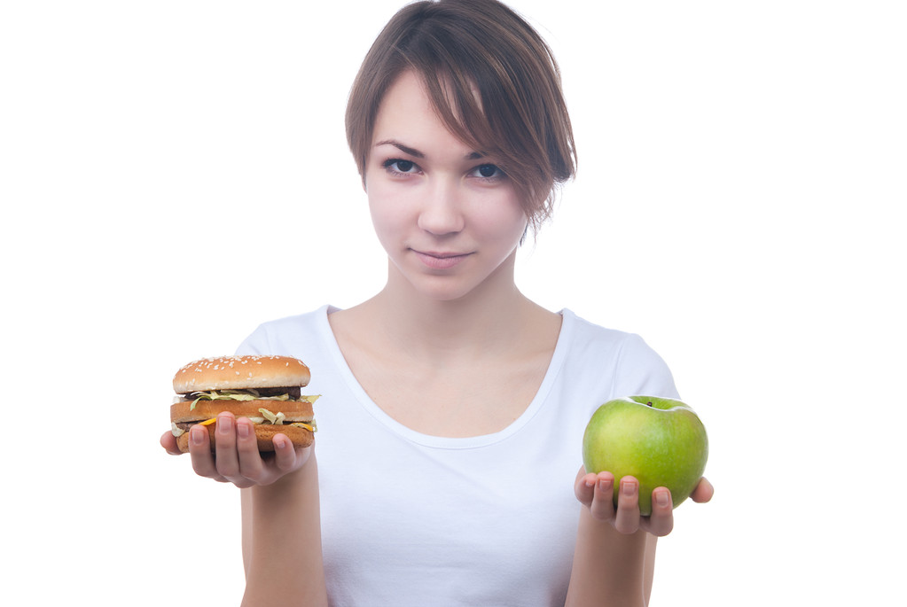 meisje maakt keuze tussen apple en hamburger - Foto, afbeelding