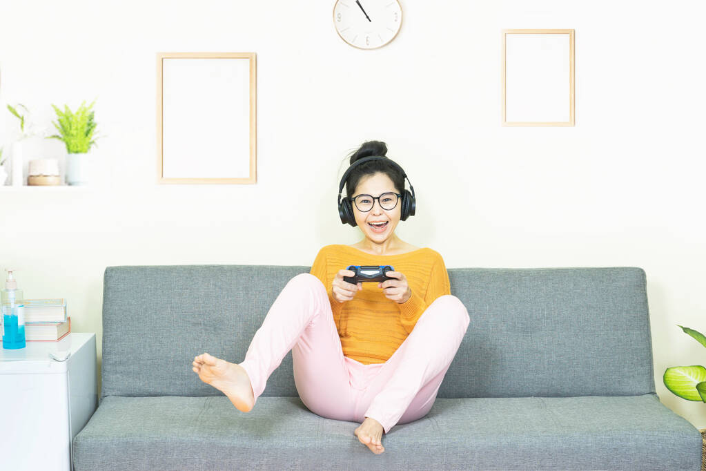 ihmiset ja vapaa-ajan konsepti onnellinen hymyilevä aasialainen nuori nainen, jolla on peliohjain pelaamassa videopelejä konsolilla hauskaa, lepää viikonloppuisin kotona karanteenissa - Valokuva, kuva