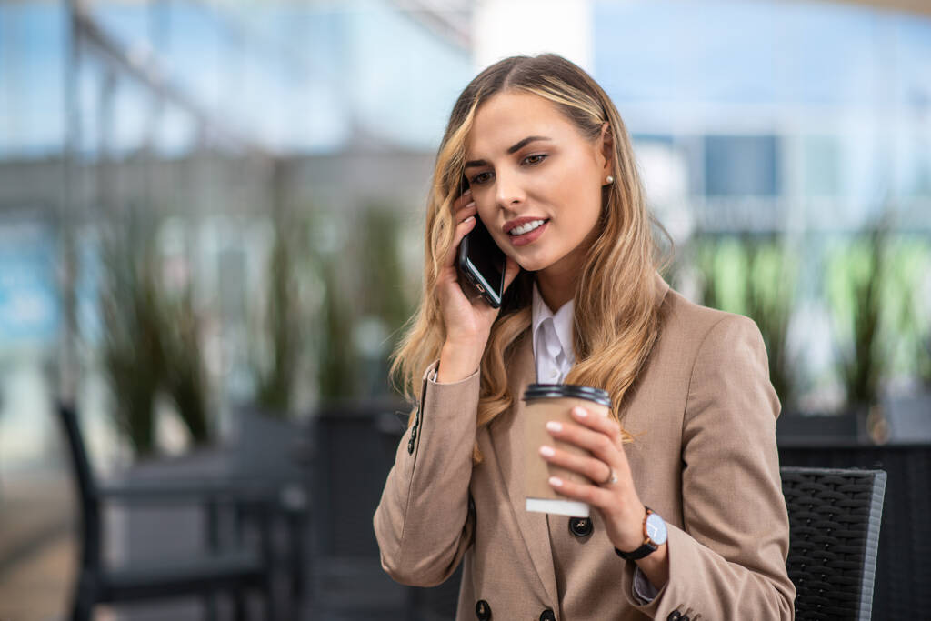 Νεαρή επιχειρηματίας σε ένα διάλειμμα για καφέ μιλάει στο τηλέφωνο - Φωτογραφία, εικόνα