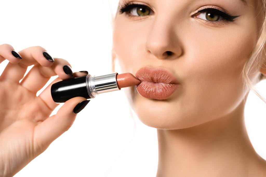 close-up uitzicht van mooie vrouw met beige lippenstift in de buurt van lippen geïsoleerd op wit - Foto, afbeelding