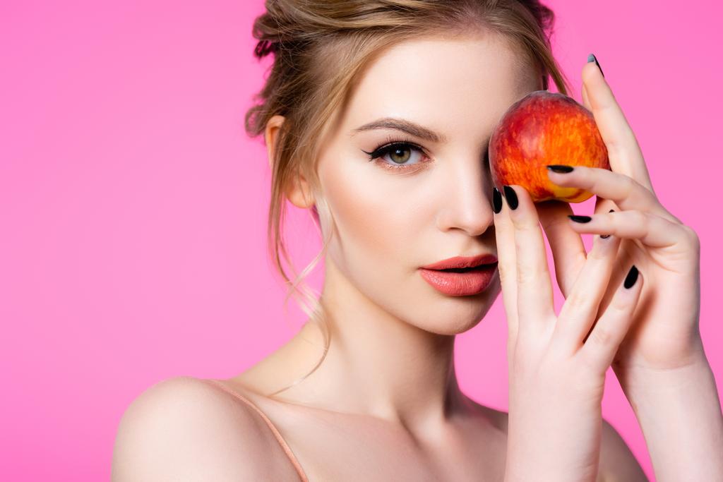 elegant beautiful blonde woman holding peach isolated on pink - Photo, Image