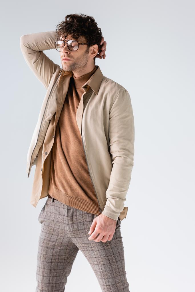 trendikäs mies silmälasit koskettaa hiuksia poseeratessaan suljetuin silmin eristetty harmaa - Valokuva, kuva